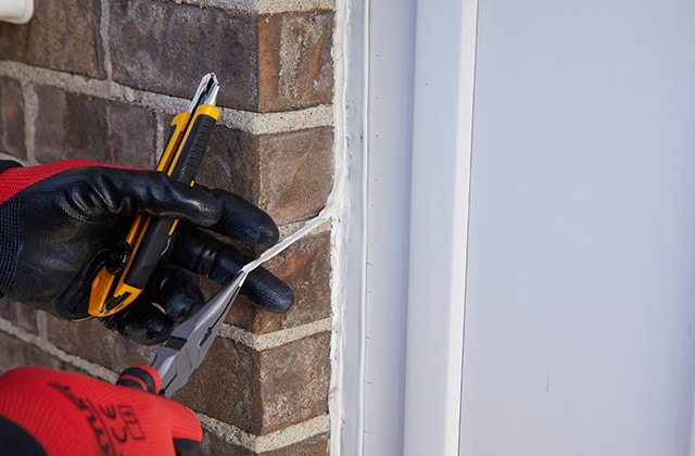 Person removing a long strip of caulk