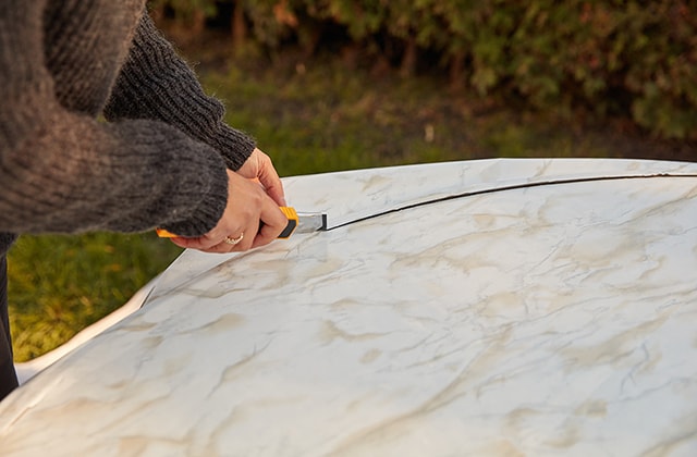 Person applying self-adhesive film to a patio table
