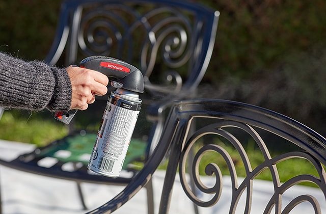 Person spray painting a patio chair