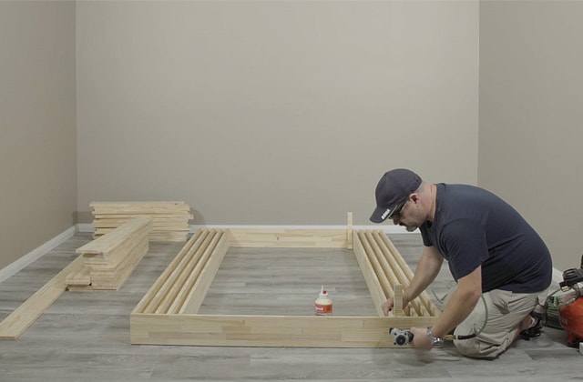 Person assembling a wood structure on the floor