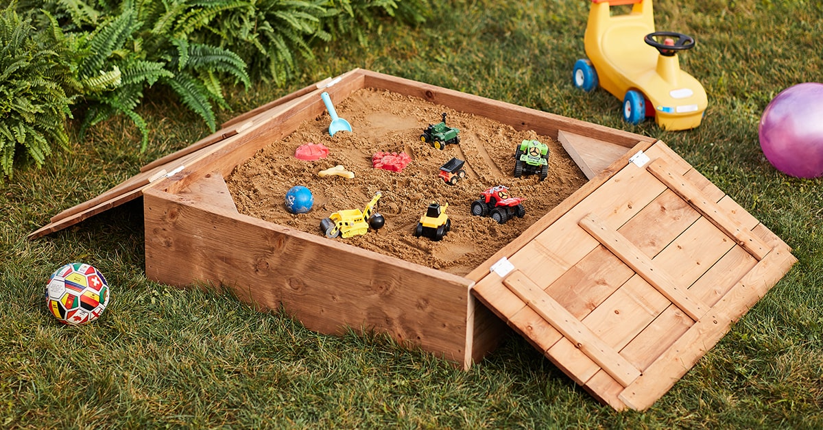 Wooden sanbdbox with a lid in a backyard