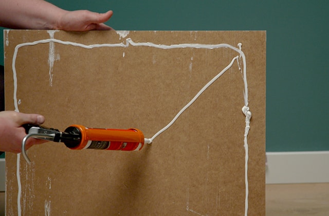 Person applying construction adhesive with a caulk gun