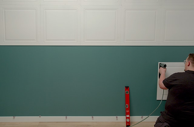 Person installing tiles on the lower part of a wall