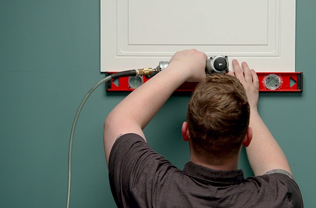 Person installing a tile on a wall