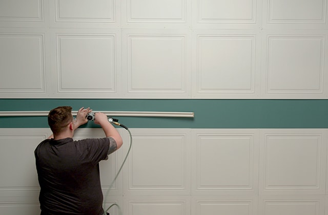Person nailing a chair rail in place