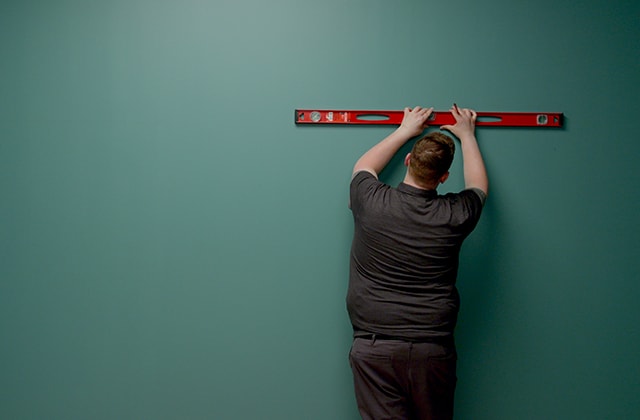 Person tracing a horizontal line on a wall