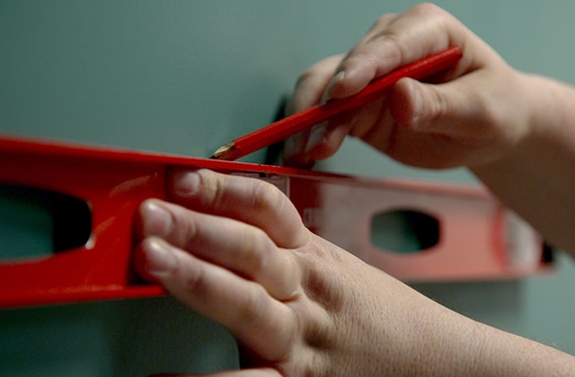 Person using a level to trace a line on a wall