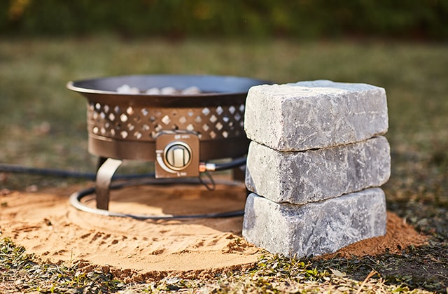Three cinder blocks stacked beside a gas fire pit