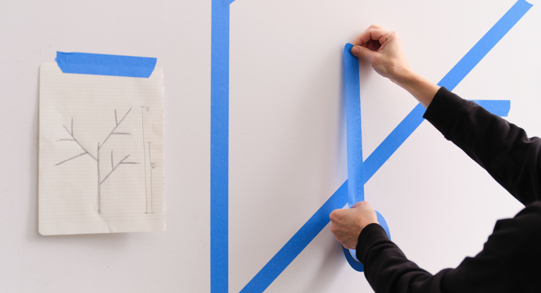 Personne qui trace le croquis de l’arbre au mur avec du ruban masqué