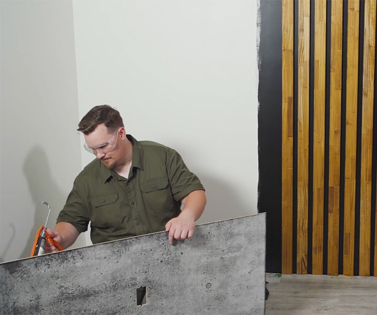 Man applying construction adhesive on a wall panel