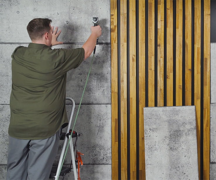 Man nailing a wall panel onto a wall