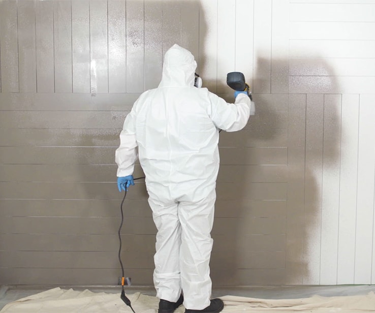 Man using a power sprayer to paint a wall