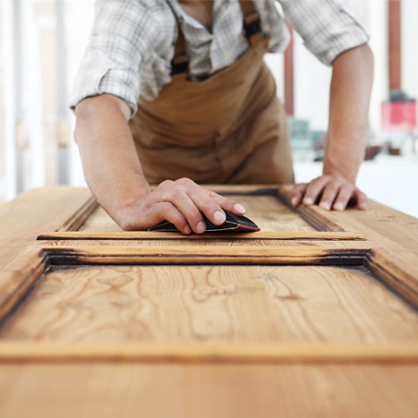 Man sanding a wooden door Man sanding a wooden door