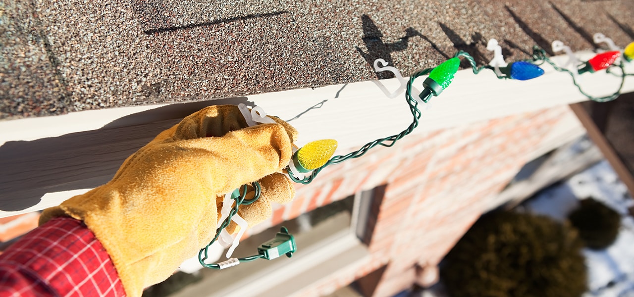 Person installing Christmas lights on a roof