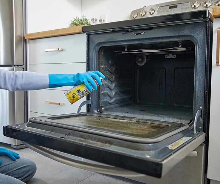 Woman cleaning a kitchen range oven