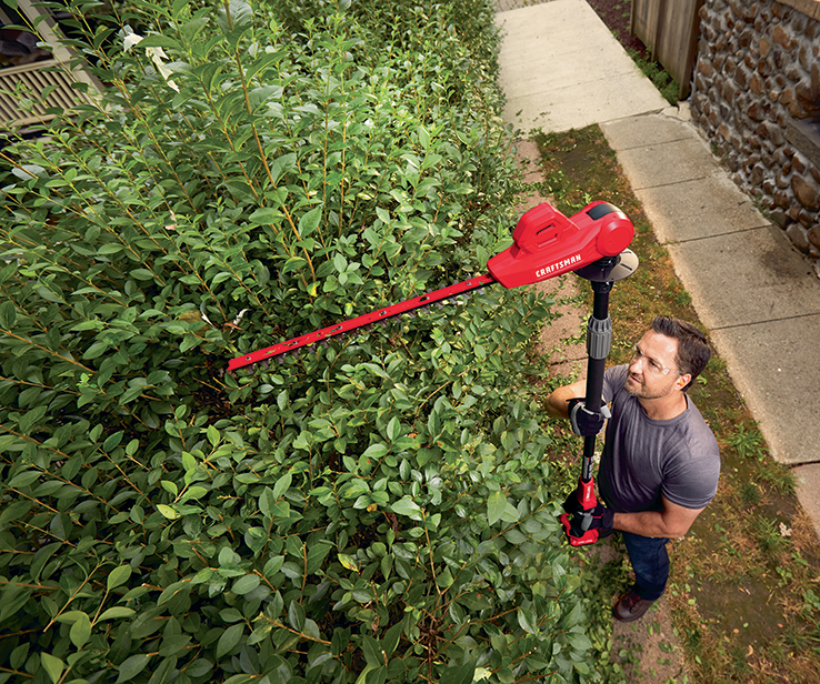 Person using a pole hedge trimmer