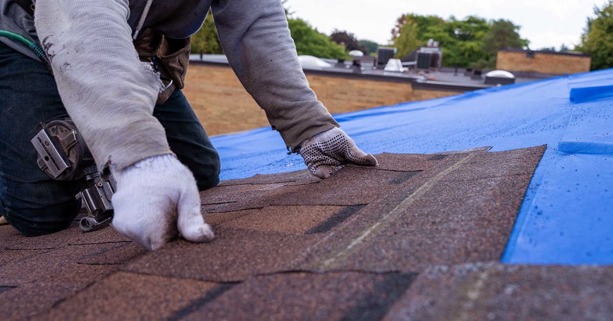 Man installing asphalt shingles on a roof