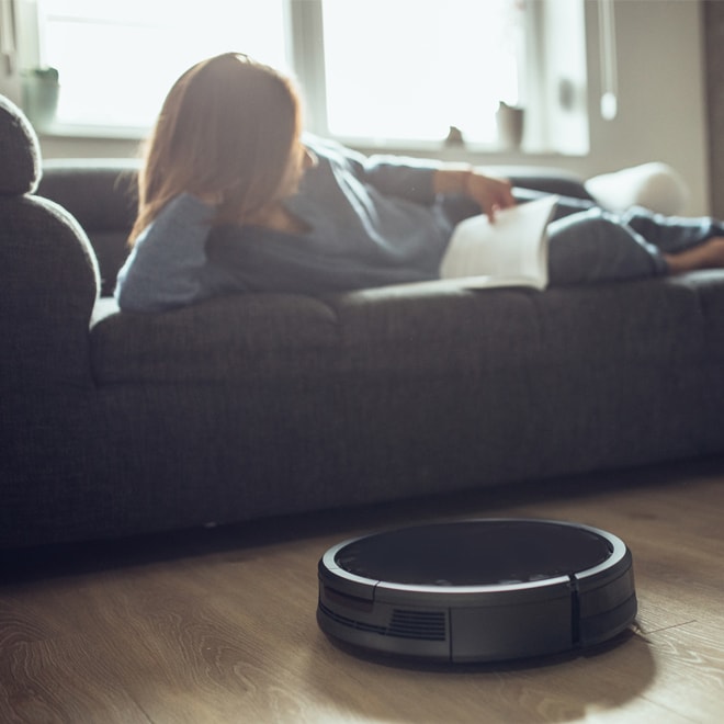 Woman reading on a couch with a robotic vacuum
