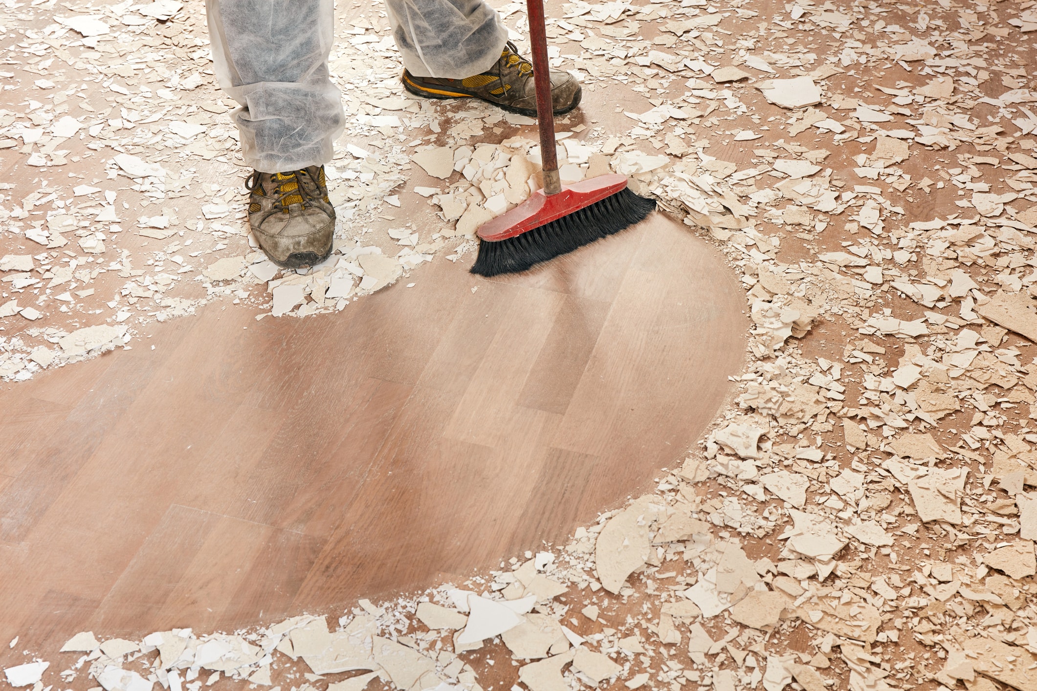 Person cleaning a floor covered in building supplies Person cleaning a floor covered in building supplies