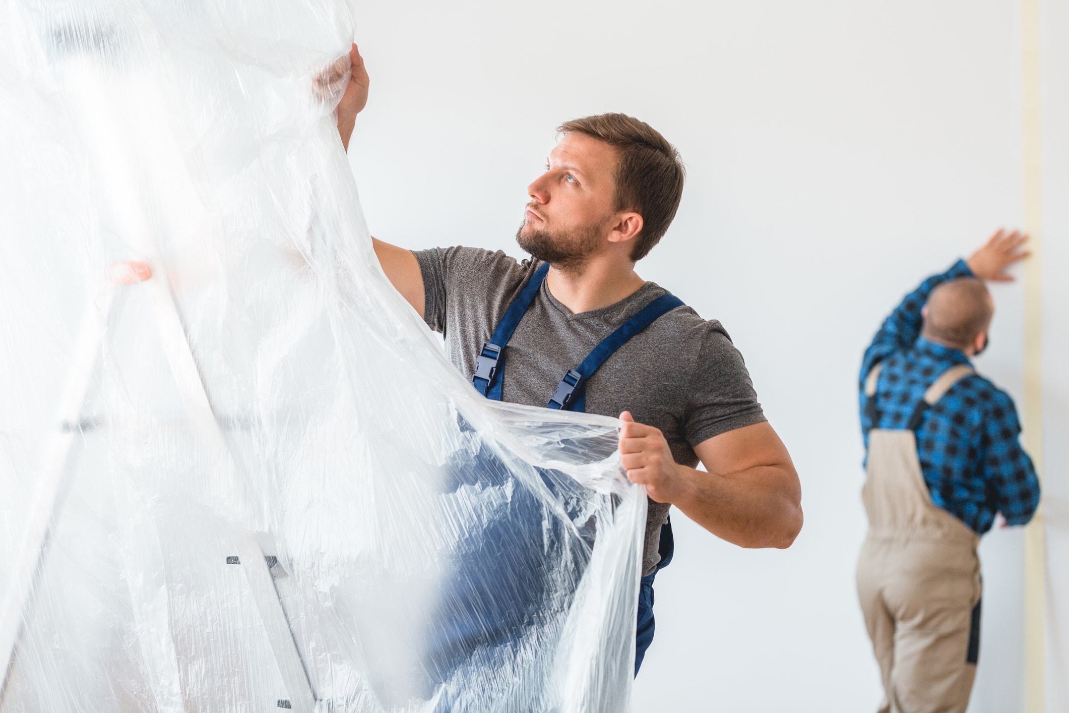 Man setting up a plastic drop sheet Man setting up a plastic drop sheet