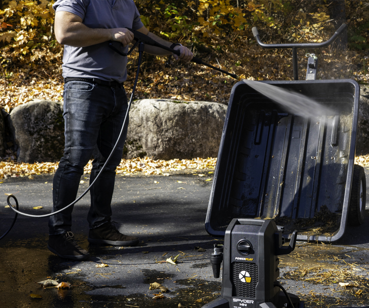 Woman using a pressure washer on a concrete deck