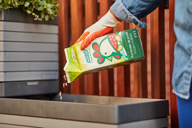 Person adding organic hen manure to a planter box Person adding organic hen manure to a planter box