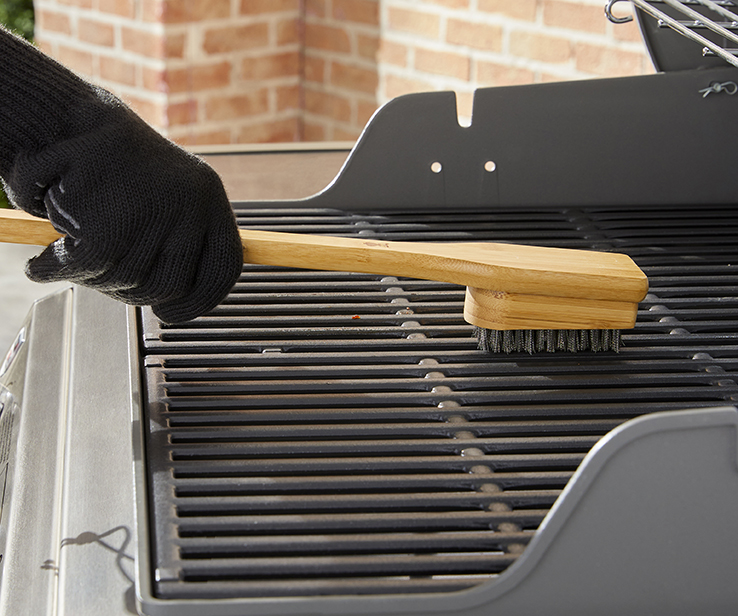 Personne nettoyant un barbecue à l’aide d’une brosse Personne nettoyant un barbecue à l’aide d’une brosse