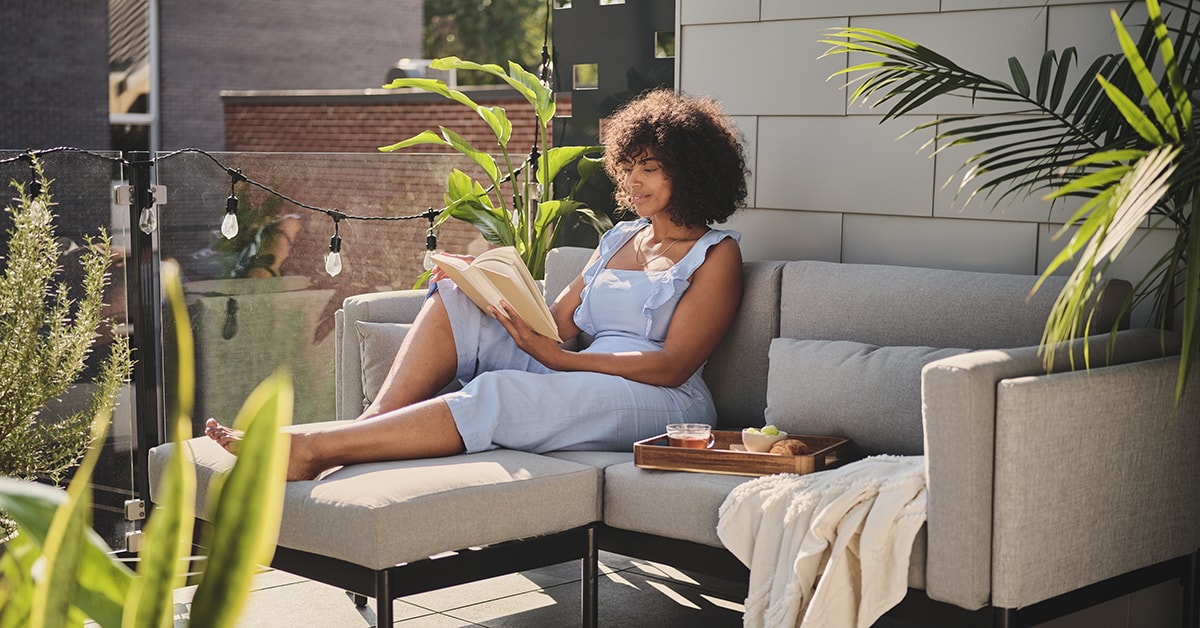 Femme lisant sur une terrasse bien décorée